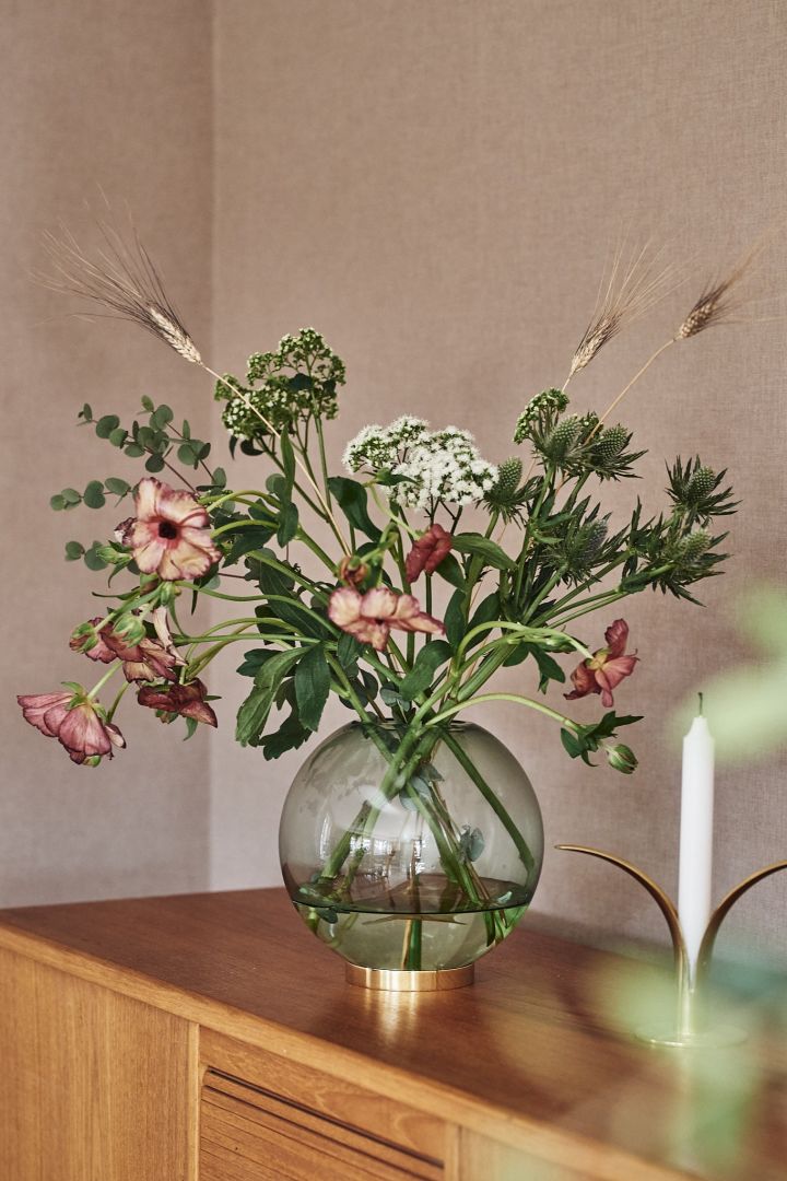 En rund vase i en nuance af grøn farvet glas. Denne runde vase er fra AYTM og har plads til en masse blomster fra Blombruket.