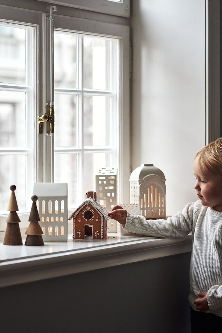 Pynt op med traditionelt skandinavisk julepynt som Urbania-lysestagerne fra Kähler. Her ses en samling af dem i vindueskarmen sammen med en lille dreng. 