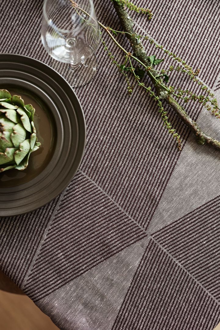 Den geometriske borddug fra NJRD i brun med en brun lines tallerken og en grøn artichoke.