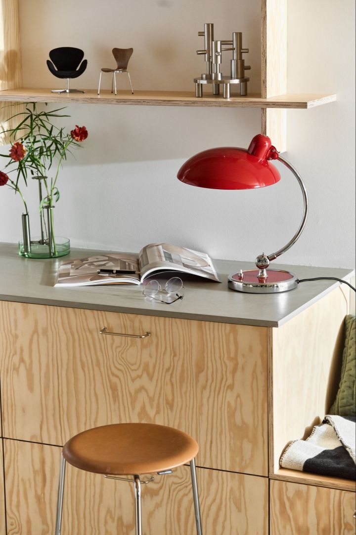 Aquí puede ver varios productos de Fritz Hansen en un rincón de lectura de una cocina
moderna. Puedes ver la lámpara Kaiser en rojo rubí y el taburete dot en cuero.