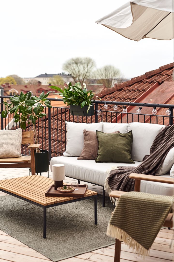 Dekorer din balkon med bløde tekstiler som denne uldplaid fra NJRD for at skabe en hjemmelig følelse.