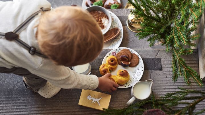 Her ser du et barn, der rækker ud efter en lussekat på en tallerken fra Rörstrands svenske Grace Winter-kollektion.