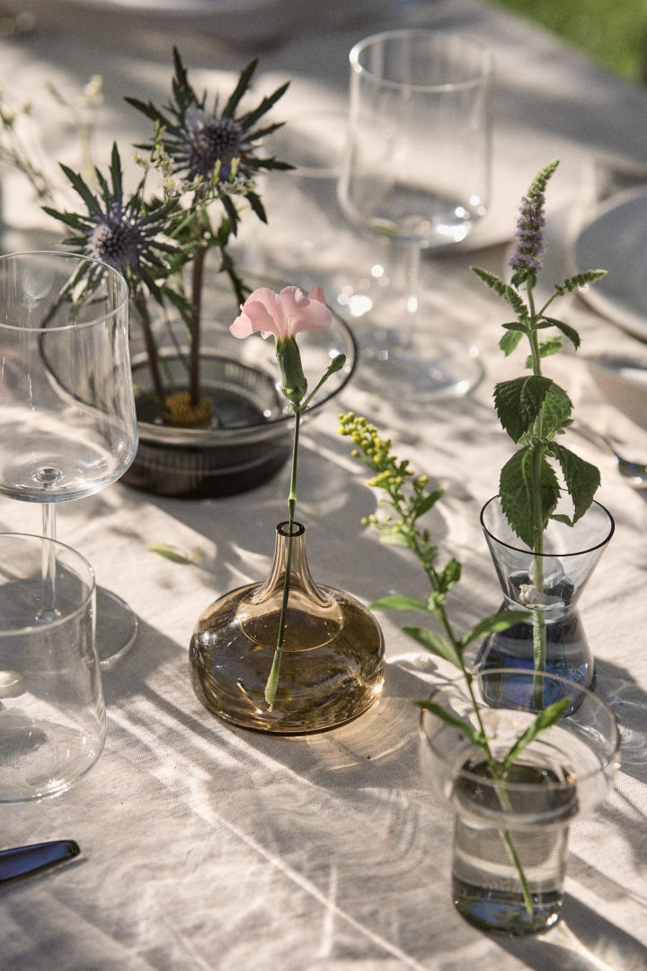 Midsommer vase sættet fra Orrefors er dækket på bordet med blomster i.