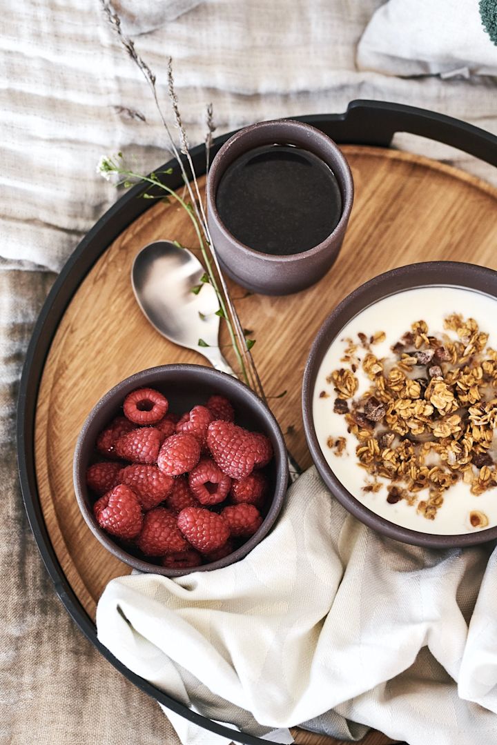 Morgenmad på sengen serveres med en flot serveringsbakke fra Eva Solo med bær og müsli i brune skåle fra Ferm Living.