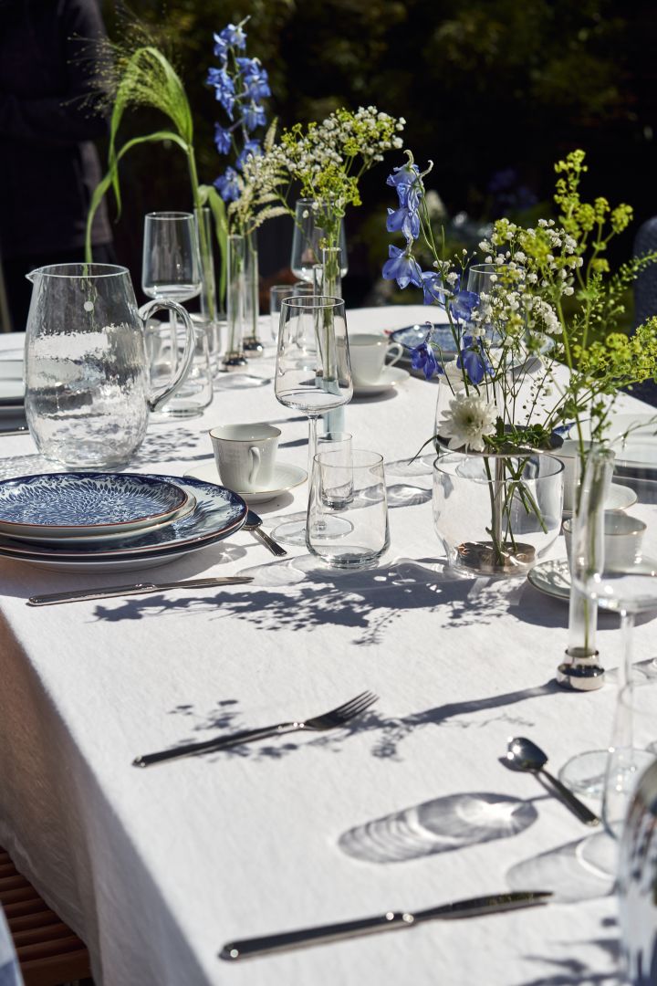 Tilføj lidt interesse til midsommer bordet med en samling af vaser og blå og hvide blomster.