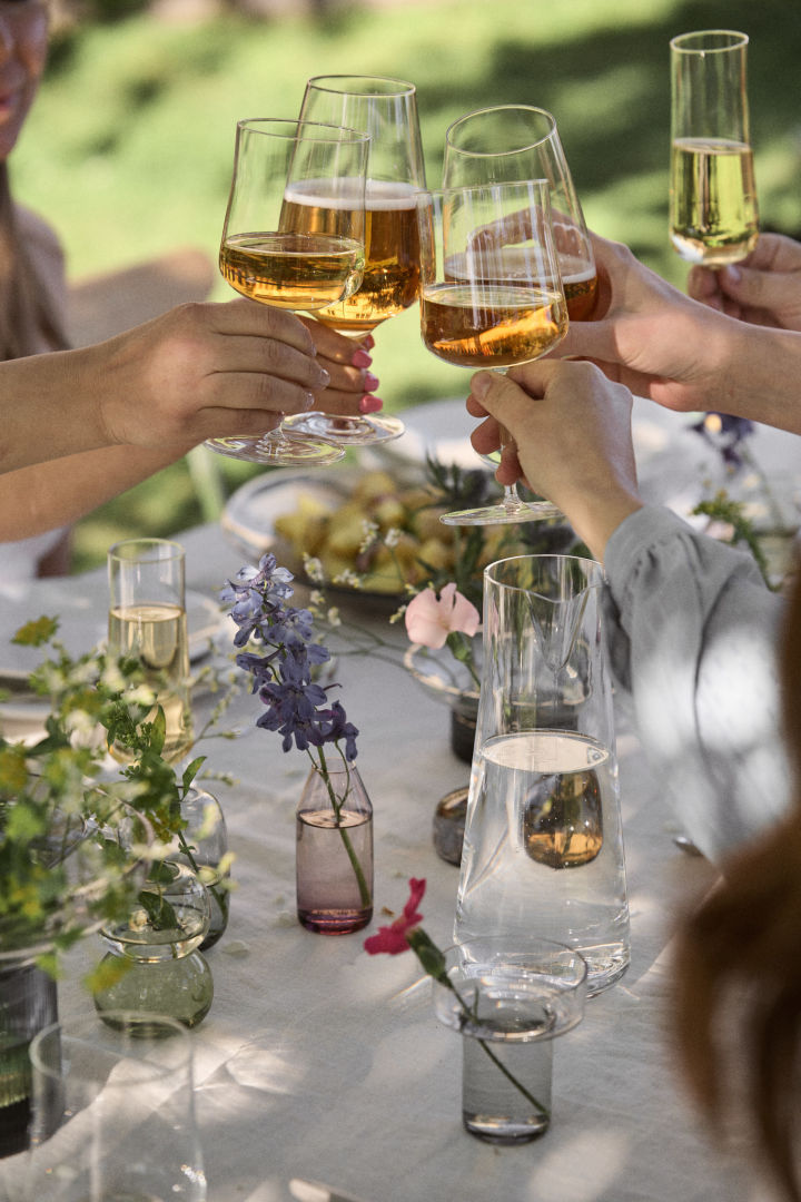 Sidder rundt om et midsommer dækket bord og klinger vinglas