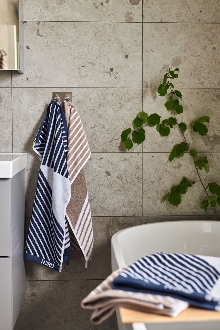 Blå og beige striped håndklæde fra NJRD der hænger i et badeværelse.