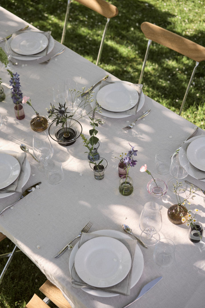 En fin, hvid og lys midsommer bordækning, dækket med forskellige Orrefors tallkerner, vaser og glas.