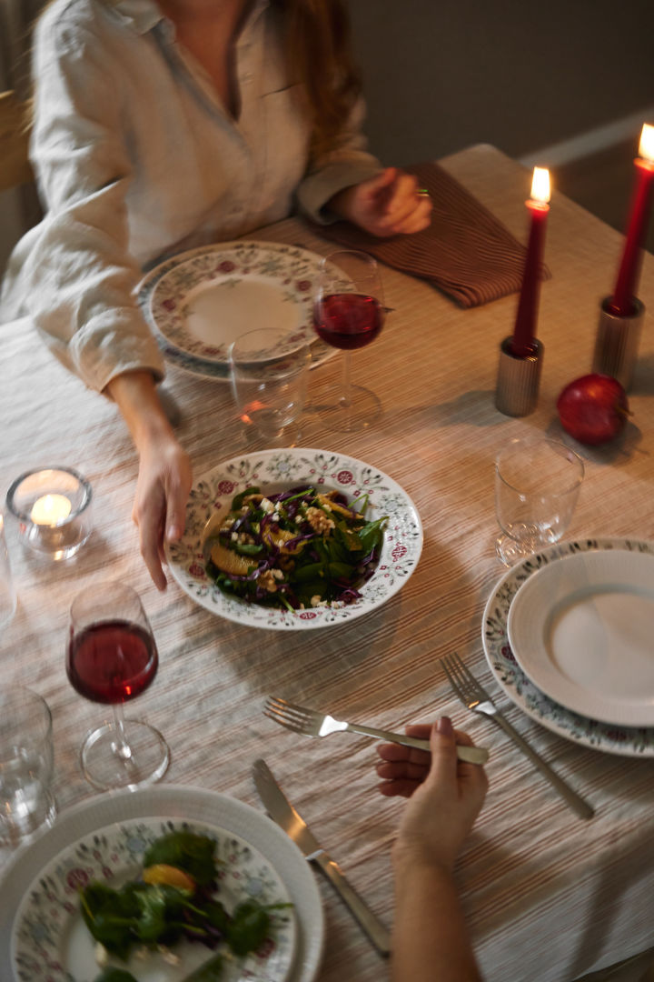 En hånd sender en vintersalat hen over bordet som en del af en skandinavisk juleborddækning. 