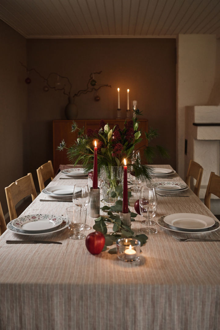 En stemningsfuld og enkel juleborddækning med røde stearinlys og printet julestel. 