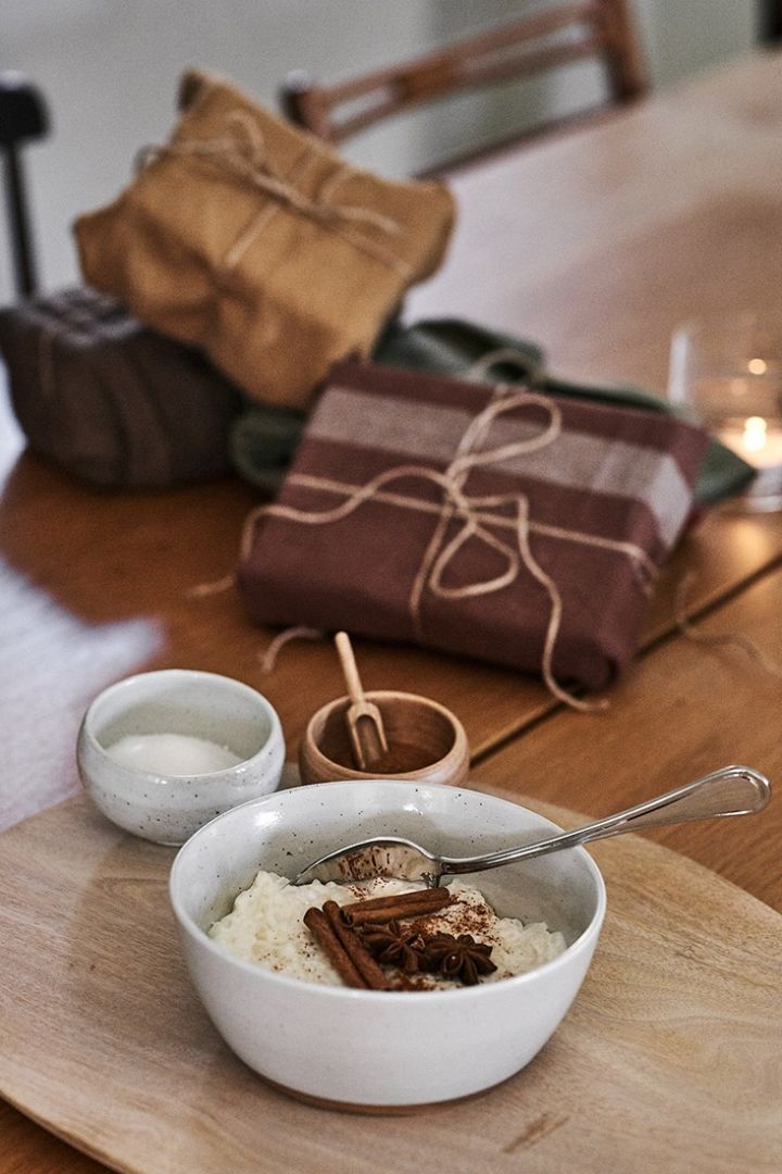 Julegrøden serveres på bordet i en rustik skål og venter på at blive nydt sammen med julehygge. 