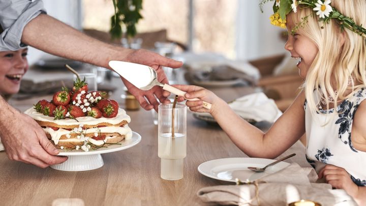 Et barn skærer den traditionelle midsommer jordbær kage.