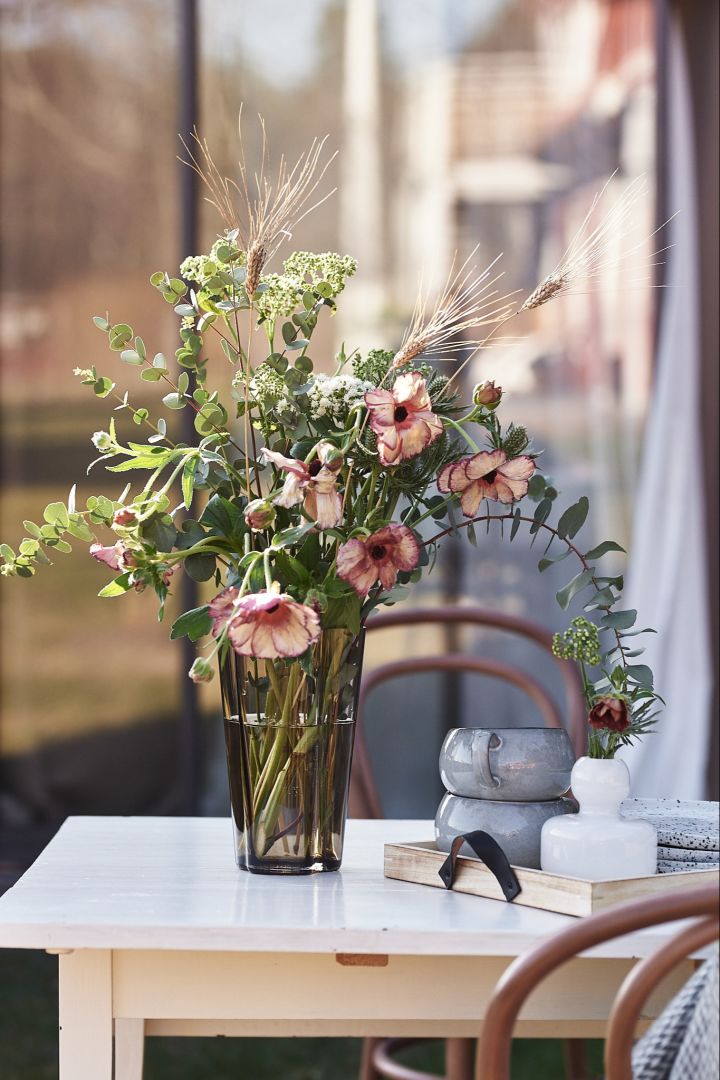 Den lige høje Aalto vase fra Iittala i et brunt farvet glas med en buket blomster fra Blombruket.